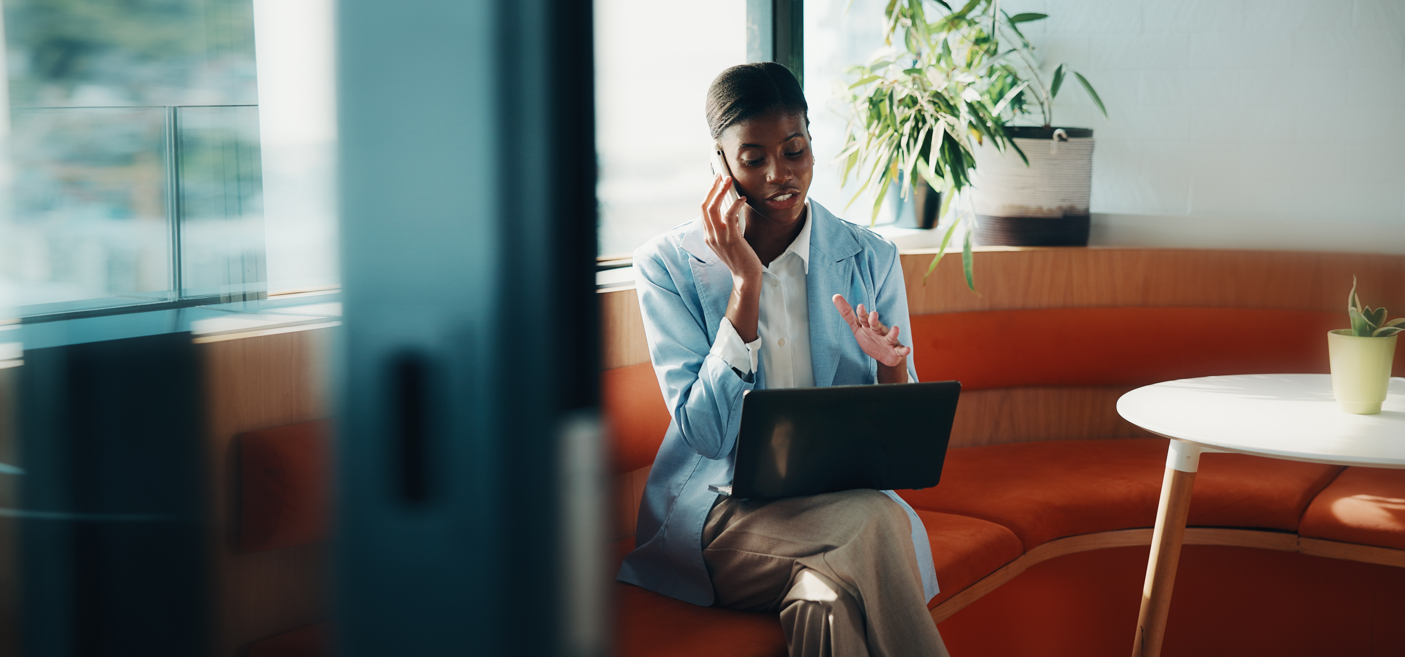 Frau im Büro im Telefongespräch mit Laptop
